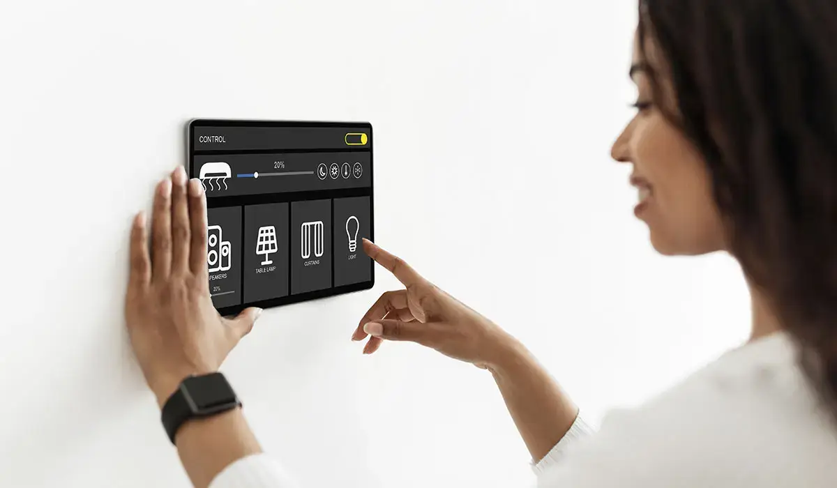 Modern smart home electronic systems concept. Pretty african american woman using smart home device, pushing button on automatic panel, setting temperature and AC at apartment, collage